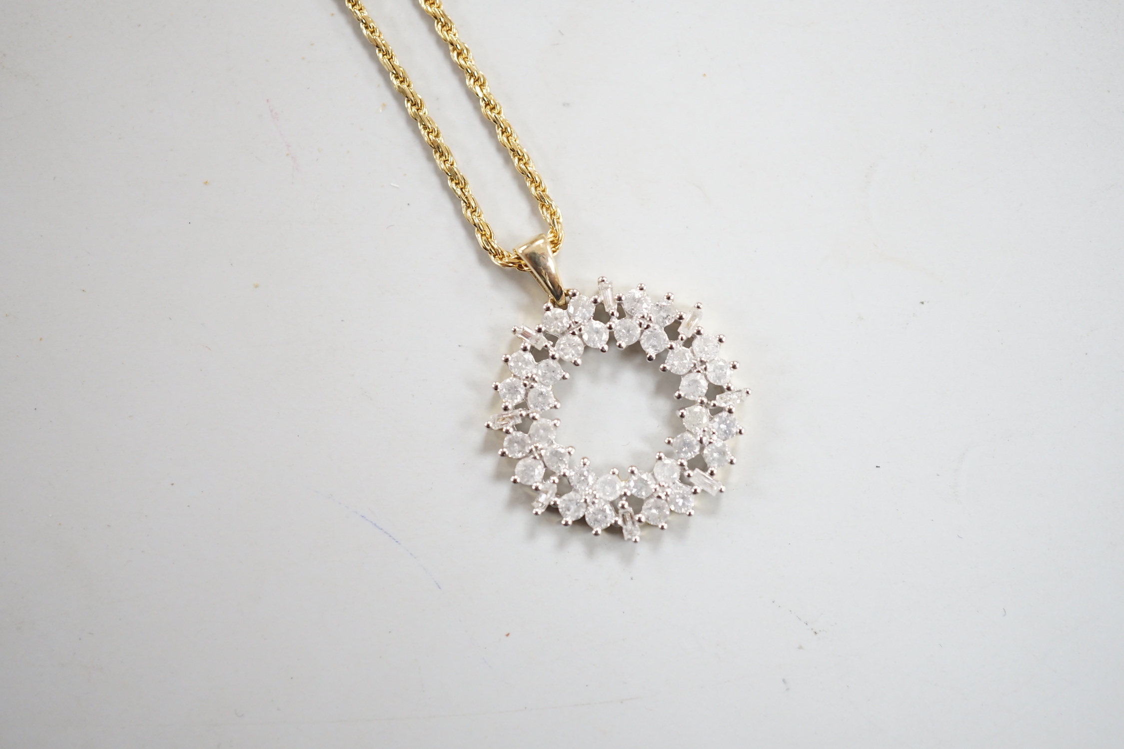 A modern 9ct gold, baguette and round cut diamond cluster set openwork pendant, diameter 17mm, gross 1.9 grams, on a modern 750 yellow metal fine rope twist chain, 48cm, 5.1 grams.